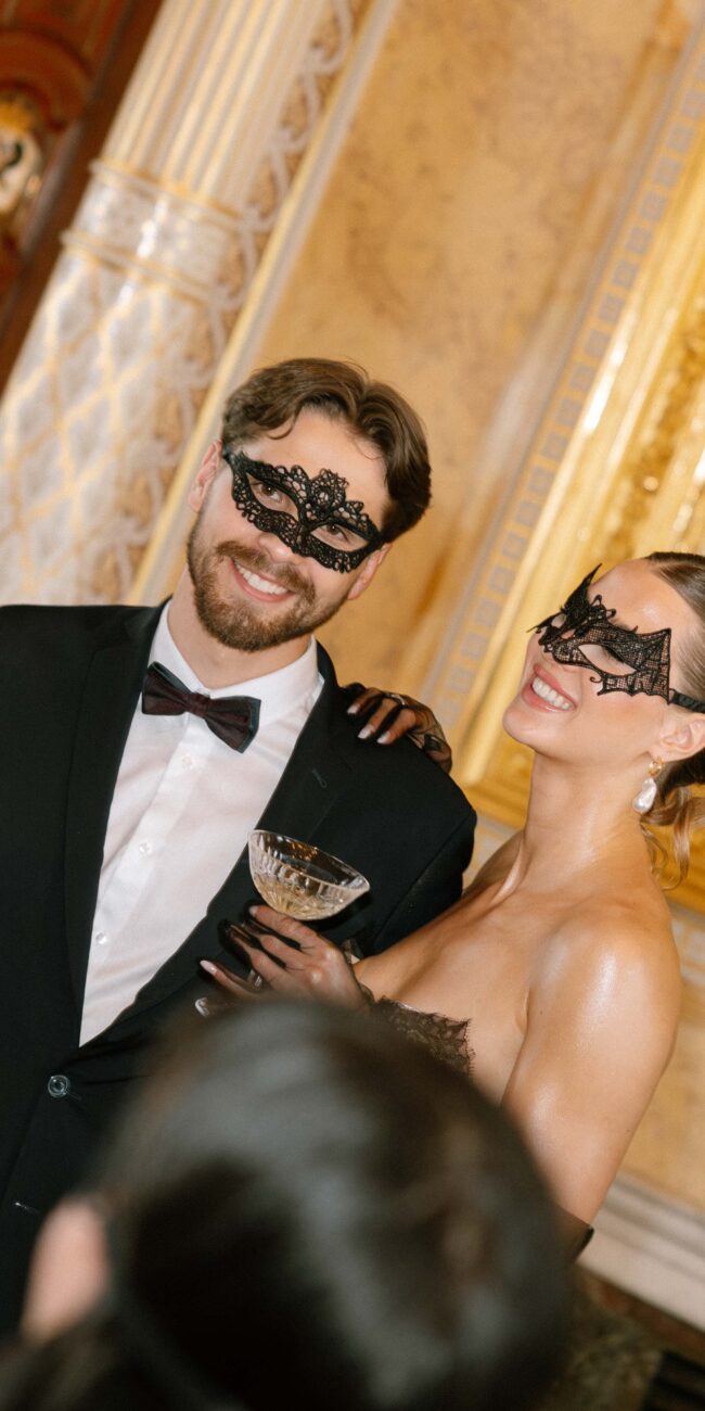 Paar mit venezianischen Masken bei einem stilvollen Maskenball