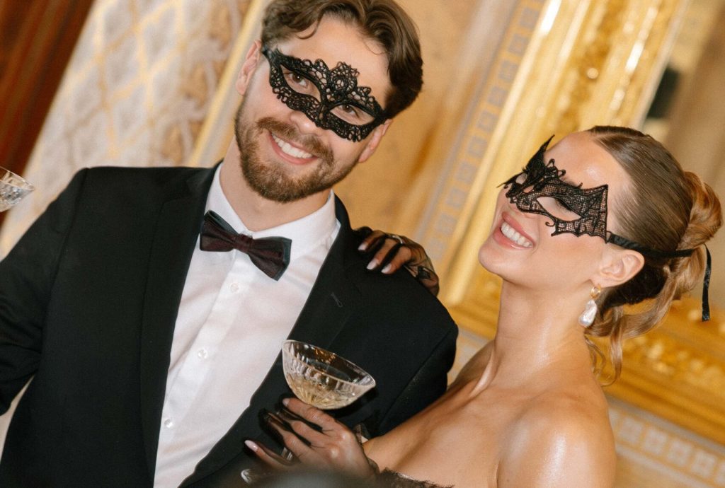 Paar mit venezianischen Masken bei einem stilvollen Maskenball